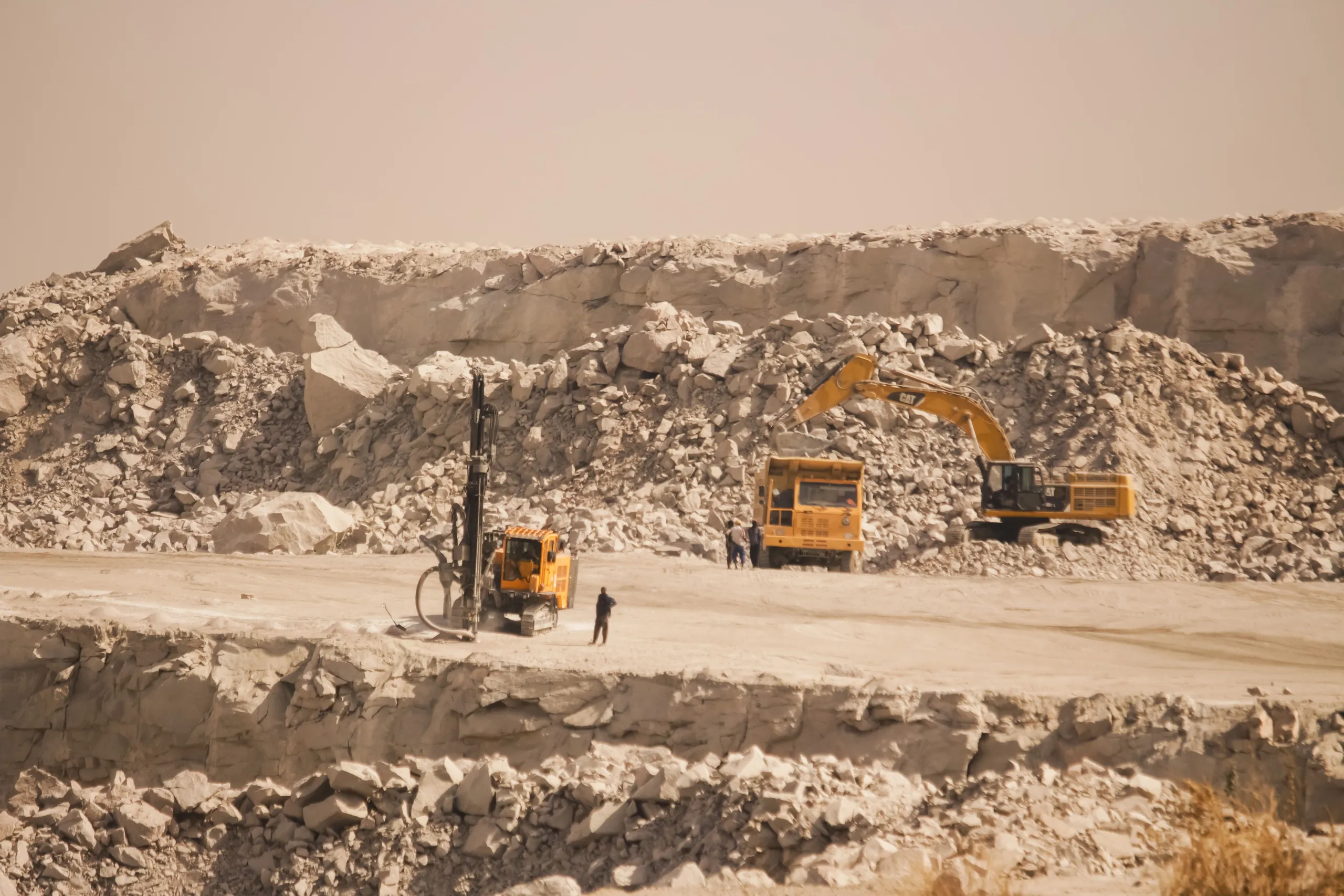 Open-pit mining site with a drilling rig, excavator and haul truck